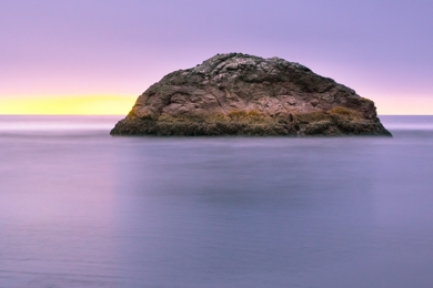 rocky island against a purplish dawn sky